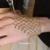 Anillo y pulsera con cadena integrada de borlas caladas europeas y americanas, pulsera de diseño único de nicho, accesorio de mano de moda resistente y exquisito