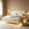 Cama grande de cuero color crema con tapicería suave y abullonada, cama flotante minimalista, dormitorio principal atmosférico con diseño suspendido y tira de luz integrada, dormitorio doble