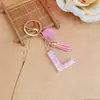 Chaveiro de letra inglesa rosa, um acessório fofo e moderno com um pompom fofo e uma franja, perfeito para projetos DIY e como pingente de bolsa para mulheres