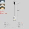 Una pequeña lámpara colgante en la sala de estar, colocada cerca del sofá, proporciona iluminación de espectro completo, creando un ambiente acogedor y atmosférico.. Es una luminaria minimalista, colgada con alambre, hecha de hierro.