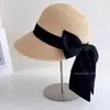Sombrero de pescador con cinta de lazo satinado mate estilo Hepburn para mujer, sombrero de paja de protección solar de verano, sombrero tipo cubo de ala de rafia con plumas