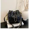 Nova bolsa de corrente bordada com padrão de losangos, uma bolsa versátil para o dia a dia para mulheres, com fecho de cordão, uma alça e um design que pode ser carregado na mão, no ombro ou na transversal.. É uma bolsa saco chique e minimalista