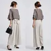 Conjunto de dos piezas en stock estilo japonés 2026: top de manga de tres cuartos de color liso con cuello redondo y mangas multicapa con corbatín, pantalones de pierna ancha