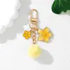 Nuevo llavero colgante de flor de pompón de flor de cerezo estilo japonés personalizado, aleación con goteo de aceite, decoración pequeña para funda de auriculares estilo Chanel