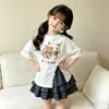Nuevo Modelo de Comercio Exterior 2026 Estilo Coreano Verano Nuevo Conjunto de Dos Piezas para Niñas con Estampado de Oso, Top de Manga Corta Dividido y Falda Plisada a Cuadros