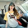 Camiseta de Manga Curta com Ombro Reto Estilo Americano para Mulheres 2026 Novo Verão Estilo Coreano Design Xadrez Top Solto com Estampa de Letras