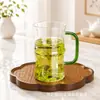 Taza de té transparente de vidrio de borosilicato grueso de alta calidad personalizada para uso en la oficina y el hogar, taza de vidrio transparente con asa de color para té verde