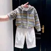 Ropa infantil coreana 2026 otoño e invierno nueva moda suéter de punto gris a rayas con corbata de lazo pantalones blancos anchos para niños modernos