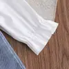 Conjunto de dos piezas fresco y lindo para niña: camisa blanca de manga larga con cuello de muñeca combinado con una falda de mezclilla con tirantes bordada de fresas.