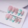 Unhas postiças feitas à mão em cores contrastantes rosa claro e azul menta com pequenas flores brancas 3D e contas redondas metálicas, formato amêndoa, estilo delicado e feminino