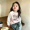 Camiseta infantil de algodão puro com blocos de cor e mangas compridas, corte solto, novo estilo 2026, design de desenho animado, moderna para primavera e outono, adequada para crianças mais velhas como camada base