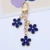 Nuevo llavero colgante de flor colorida ins, creativo, aleación DIY, flor pequeña de doble cara, decoración para funda de auriculares, bolso