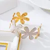 Un brazalete abierto para mujer, sencillo, de esmalte floral, versátil para el uso diario.