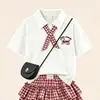 2026 Novo Estilo Suéter College Doce de Manga Curta para Meninas Conjunto de Verão Cartoon Estiloso Xadrez Bolo Saia Conjunto de Duas Peças