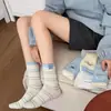 Meias de Cano Médio Bordadas em Desenho Animado Meias com Etiqueta de Tecido Listradas em Creme e Azul para Mulheres Outono e Inverno Novas Meias Slouch de Algodão Penteado com Agulha Dupla