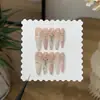 Un Set de Uñas con un Degradado Ámbar Ligeramente Borracho, Polvo Blanco Leche, Estilo Francés y Pedrería de Corazones Cromados