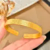Pulseira aberta em formato de coração de lótus banhada a ouro, uma peça luxuosa e sofisticada com acabamento dourado texturizado de areia, apresentando cor uniforme tanto por dentro quanto por fora.