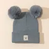 Gorro de punto para niños con doble pompón, estilo pullover para niños y niñas, etiqueta de cuero bordada linda de otoño e invierno, gorro cálido con protección para las orejas engrosada