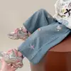 Nueva colección de otoño de ropa infantil para exportación: Jeans para niña estilo coreano 2026 con adornos de diamantes de imitación de dibujos animados, pantalones rectos modernos y elegantes, disponibles para dropshipping