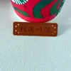 Hay disponibles en stock una variedad de etiquetas de cuero repujado con patrones de estilo coreano, etiquetas de PU que cambian de color, parches de cuero PU de imitación, parches de patchwork y etiquetas tejidas.