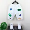 Calça Cropped Rasgada Patchwork com Apliques de Etiqueta de Verão para Meninos 2026 Nova Estilosa Casual Versátil de Sete Quartos para Crianças e Bebês