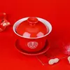 Um conjunto de xícaras de chá de casamento, incluindo um par de tigelas de chá e pauzinhos vermelhos e festivos, perfeito para servir chá durante a cerimônia de casamento.