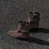 Botas de tornozelo estilo retrô com salto grosso, apresentando um design de duas vias, bico fino e detalhe de fivela de cinto, perfeitas para a estação outono de 2026