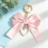 Llavero colgante de lazo de perlas en forma de corazón más vendido, muñeco de decoración de mochila con cinta colorida estilo Chanel pequeño personalizado