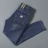 Calça jeans de sarja elástica para primavera e outono, estilo coreano slim fit, marca da moda, bordado simples, calça casual moderna e versátil para homens