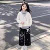 Elegante y a la moda conjunto de dos piezas para niñas para primavera y otoño: un top a rayas con un diseño de cuello único, combinado con pantalones casuales con delicados detalles de encaje - un conjunto de dos piezas moderno