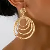 Un par de pendientes para mujer circulares, huecos, texturizados y de forma geométrica irregular, elegantes y adecuados para el uso casual diario