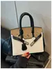 Bolso de mano de alta gama para mujer, nuevo modelo 2026, bolso Kelly de moda transfronterizo, bolso de hombro y cruzado casual para el trabajo, color platino