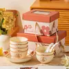 Un juego completo de cuencos, cucharas, platos y vajilla de cerámica en cajas de regalo, personalizado y práctico como recuerdo para clientes y empleados en la ocasión de la inauguración de una tienda o una celebración de aniversario.