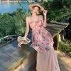 Conjunto feminino estilo francês com estampa floral rosa doce, apresentando um top de renda com gola halter e uma saia longa, perfeito para férias na praia.
