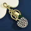 Luxuoso e requintado, este chaveiro de maçã 3D é totalmente cravejado com strass brilhantes e adornado com detalhes de folhas verdes. Disponível em várias cores.