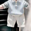 Ropa infantil coreana 2026 otoño nuevo suéter de punto con cuello polo a rayas azules conjunto de pantalones casuales blancos para niños