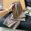 Toma real de pantalones largos casuales para mujer en un estilo relajado, con un patrón de cuadros retro color café, corte holgado, efecto adelgazante, diseño de pierna ancha y corte recto, para la colección de otoño 2026