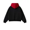 Sudadera con capucha de color bloqueado de tono oscuro, de nicho, con botones metálicos diagonales, tapeta irregular, corte holgado y hombros caídos, al por mayor