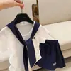 Conjunto de Camiseta de Manga Corta con Cuello Azul Marino Bordado de Letras para Niñas, Falda Corta Lisa Elegante de Verano para Niños, Atuendo Estilo Universitario