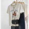 Camiseta Estampada Retro Americana Branca Leite Cinza para Mulheres Verão 2026 Solta Casual Emagrecedora Top Algodão Puro Ombro Direito Manga Curta