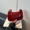Bolsa de ombro feminina em couro envernizado brilhante, modelo baguette, estilo moderno e versátil, ideal para viagens internacionais em 2025. Perfeita para usar no ombro ou sob a axila.