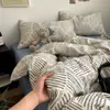 Juego de cuatro piezas de algodón acolchado con estampado de rayas minimalista con sábana bajera y funda de edredón de doble cara