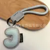 Venta al por mayor transfronteriza de llaveros japoneses y coreanos con letras en inglés, dijes para bolso de cuero dopamina, pequeños accesorios y regalos