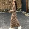 Nova coleção de outono: um vestido longo de manga comprida, acinturado, afina a silhueta, com listras color block e uma sobreposição estilo xale, combinado com uma saia longa que molda o corpo - um conjunto de duas peças