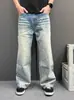 Calça jeans masculina de sarja azul claro com degradê, bainha curva, lavada e com aspecto desgastado, perna larga levemente flare, modelagem relaxada, calça casual versátil