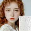 Adesivos faciais de Natal, apresentando um design de árvore de Natal com verso autoadesivo, sem necessidade de cola. Inclui designs de floco de neve, coração e estrela para maquiagem dos olhos e outras aplicações cosméticas