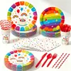 Decoraciones para fiesta de cumpleaños infantil con temática de arcoíris, que incluyen platos de papel desechables, pancartas, banderines y artículos decorativos