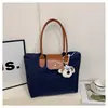 Bolsa de mano de nailon de color contrastante estilo coreano, cuerpo de bolsa de nailon con detalles de cuero marrón y un dije de cachorro de peluche, bolso de hombro para estudiante