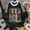 Camiseta Estampada com Letras e Personagens de Marca Tendência Patchwork de Três Listras Manga Curta 2026 Novo Estilo de Verão Ins Casual Solta