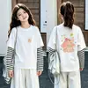 Camiseta de manga larga tipo dos piezas de imitación para niños, colección otoño 2026, para niñas, 100% algodón, cuello redondo, corte holgado, diseño lindo de caricatura, top básico
